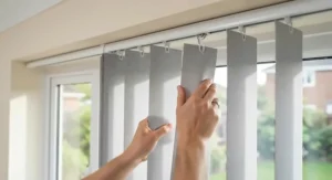 Hands clipping replacement vertical blind slats securely into the existing ceiling-mounted headrail.